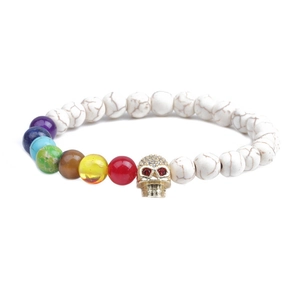 Detail of white turquoise beaded bracelet with chakra stones and gold skull charm