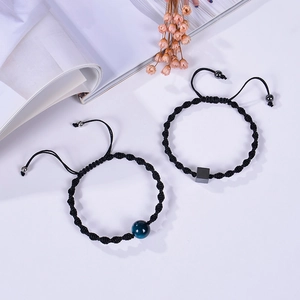 Detail of adjustable black braided bracelets with blue and grey stone charms on magazine