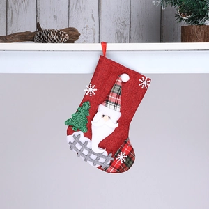 Detail of red linen Christmas stocking with 3D Santa Claus hanging on wooden wall