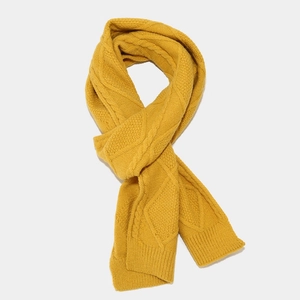 Detail of ginger yellow knitted scarf featuring chunky cable and diamond stitch textures