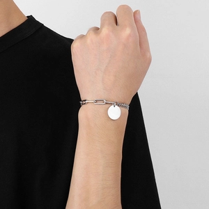 Gros plan du bracelet à double chaîne argentée avec pendentif rond porté au poignet