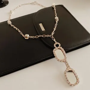 Silver-tone long necklace with vintage glasses pendant and square crystal on leather bag
