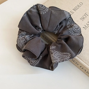 Detail of dark grey oversized scrunchie featuring white paisley patterns and soft fabric texture