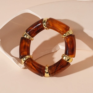 Macro view of vintage amber acrylic bamboo bracelet with gold polished metal spacers