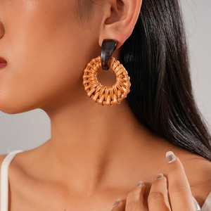 Close-up of a bohemian brown rattan round earring worn by a model for resort style