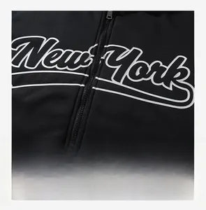 Détail de l'imprimé New York et de la fermeture éclair argentée sur une veste noire à capuche