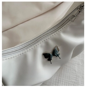 Detail of white square bag featuring silver zipper and contrast butterfly metal buckle