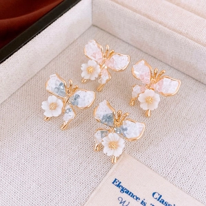 Elegant butterfly stud earrings with crystal wings and small flower accents in jewelry box