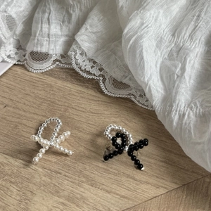 Detailed macro view of woven beaded bow rings in black and white pearl styles