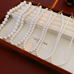Gros plan de colliers de perles blanches en quatre tailles avec fermoirs dorés