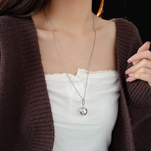 Detailed view of a silver titanium steel ball pendant necklace worn on a model