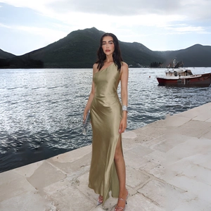 Detailed view of elegant olive green satin dress with side slit on a scenic bridge