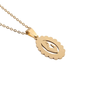 Macro shot of gold oval filigree pendant showing mother holding child on metal necklace