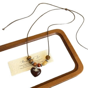 Vintage wooden beaded necklace featuring a dark red heart pendant and rustic woven cord
