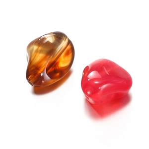 Macro detail of irregular acrylic beads in amber brown and vibrant rose red with holes