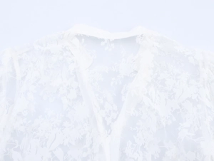 Detailed macro view of white mesh top featuring floral embroidery and V-neckline cut