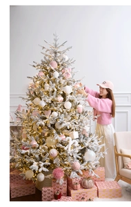 Detail of flocked Christmas tree with pink ornaments and warm LED lights for holiday decor