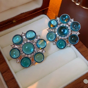 Close-up of vintage flower earrings with blue gems and clear rhinestones in a wooden box