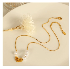 Détail du collier pendentif cœur avec quatre perles sur une chaîne en acier inoxydable doré