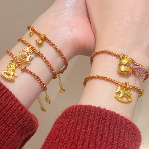 Détail de bracelets en corde rouge plaqués or 24K avec breloques cheval et gourde festifs