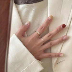 Primo piano di anelli minimalisti impilabili in oro e argento indossati su un dito