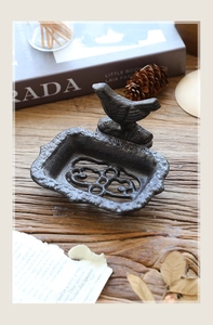 Detailed view of vintage cast iron soap dish with bird ornament and drainage holes