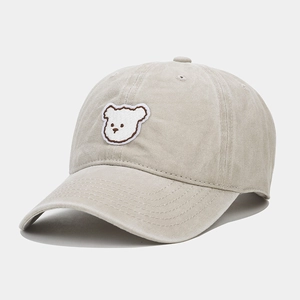 Detail shot of a cute white bear embroidery patch on a washed beige baseball cap