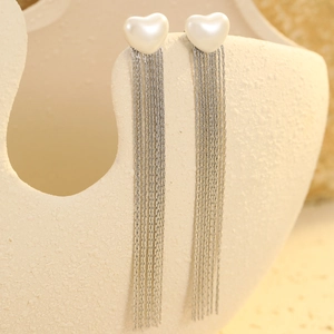 Detail view of heart pearl earrings with elegant silver metal chain tassels on stand