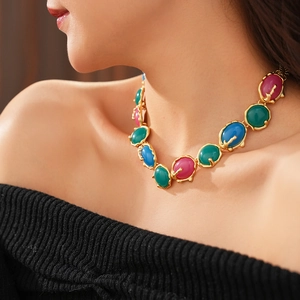 Détail d'un collier vintage doré avec des breloques ovales en résine verte, bleue et rose