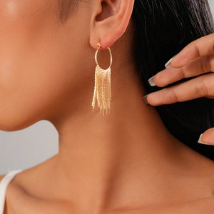 Detailed view of a gold geometric tassel earring with shimmering metal chains on a model