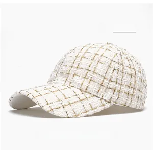 Gros plan sur la texture du tweed blanc cassé avec des fils dorés sur cette casquette