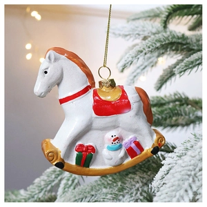 Close-up of white painted Christmas rocking horse ornament hanging on a snowy tree branch