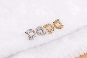Macro detail of C-shaped stainless steel earrings with white enamel and sparkling crystals