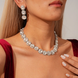 Detailed view of luxury silver necklace and earrings set with oval crystals on model