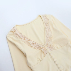 Close-up of the elegant lace trim v-neckline and pearl buttons on a yellow knit top