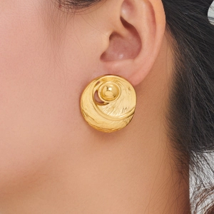 Detail of hammered C-shaped sunflower earrings with pearl inlay and golden finish