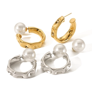 Minimalist irregular C-shaped gold and silver earrings with large pearls on white background