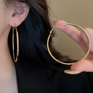 Detail showing high-polish gold hoop earrings on model and handheld close-up view