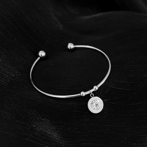 Close-up of silver titanium steel open bangle with a clear crystal round pendant