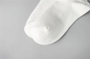 Detailed close-up of smooth toe seam and flat cotton knit texture on white sports socks