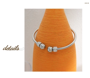 Close-up of silver steel screw pattern bracelet with white rhinestones and bead detail