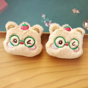 Close-up of cute plush brown bear accessories with embroidered green glasses and berries