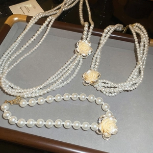 Detailed view of multilayer pearl necklaces with diamond rose pendants on a jewelry tray