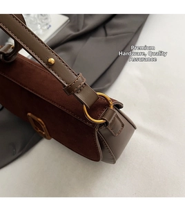 Detail of brown vintage suede shoulder bag featuring gold ring hardware and buckle closure