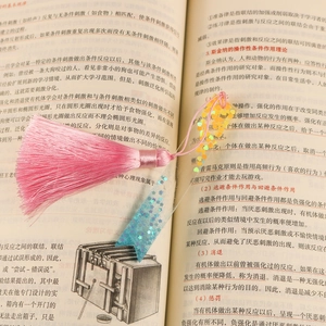 Detail of DIY bookmark with pink silk tassel and starry blue sequin ribbon on a book