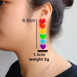 Rainbow acrylic heart drop earrings worn by model with 6.6cm length dimension detail
