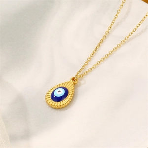 Golden stainless steel necklace with evil eye teardrop pendant on marble background