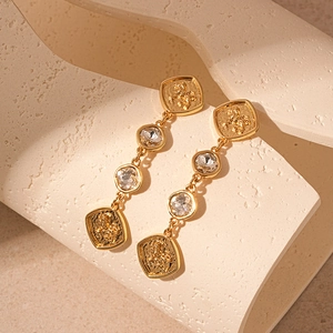 Detail of vintage gold earrings with lion embossment and sparkling cubic zirconia stones