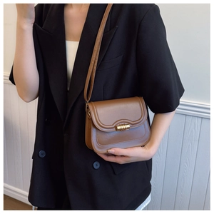 Close-up of brown vintage leather crossbody bag featuring a golden metal twist lock buckle