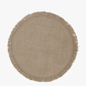 Round natural jute placemat with fringe edges for dining table in boho minimalist style